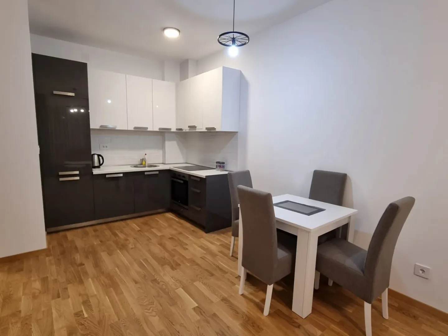 Modern kitchen with white and dark cabinets and a dining table with four chairs.