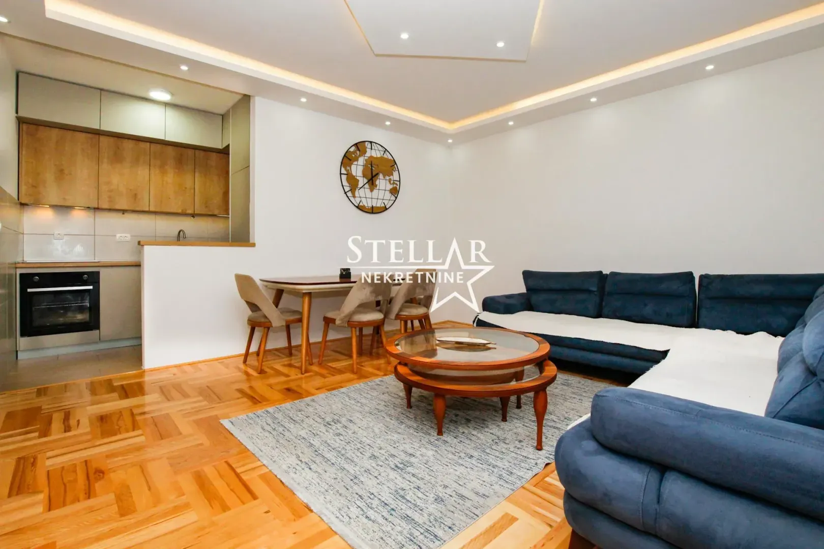 Living room with a sofa, dining area, and kitchen in the background.