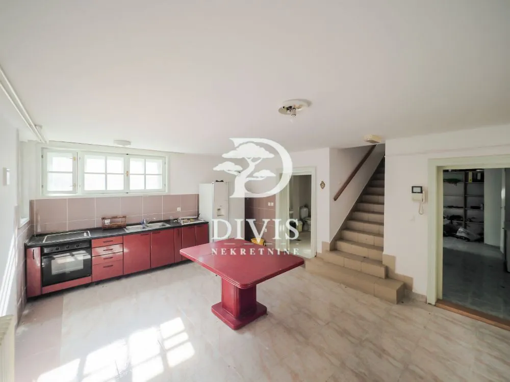 Spacious kitchen with red cabinets, dining table and staircase.