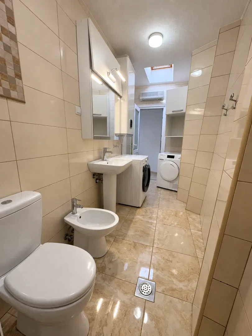 Svijetlo opremljeno kupatilo sa sanitarijama i veš mašinom.