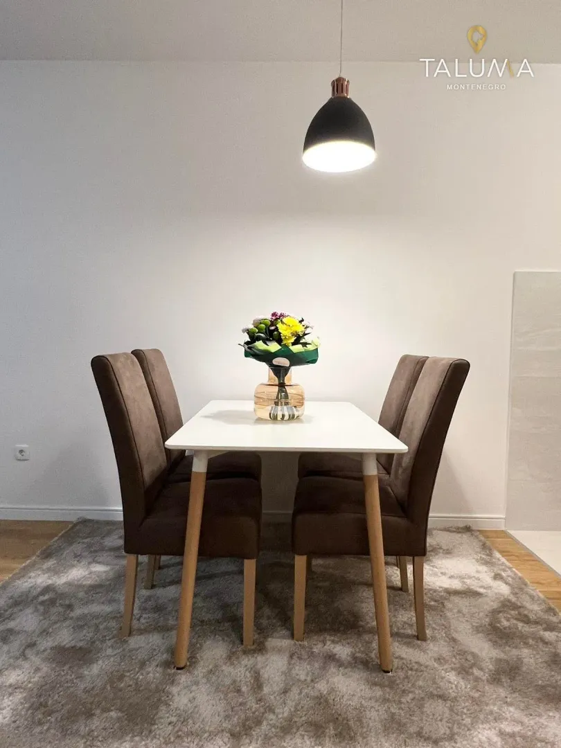 Dining table with four chairs and a pendant light above.
