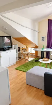 Dnevna soba u potkrovlju sa TV-om, stolom i kaučem. - image 4