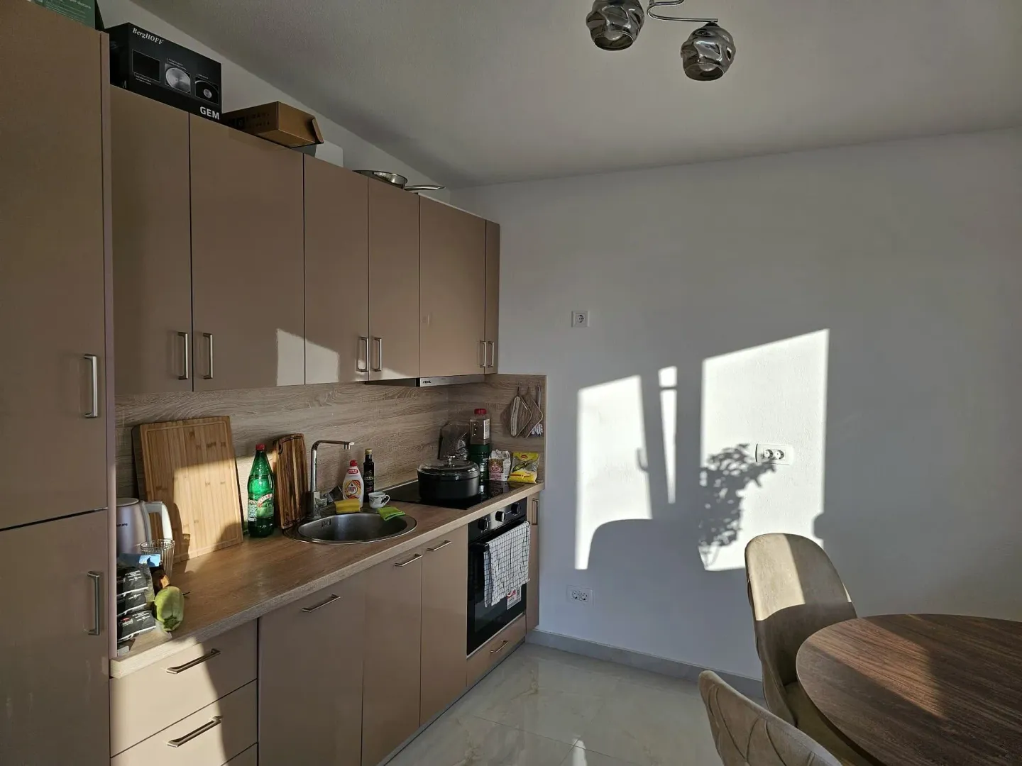 Kitchen with beige units and a dining table.