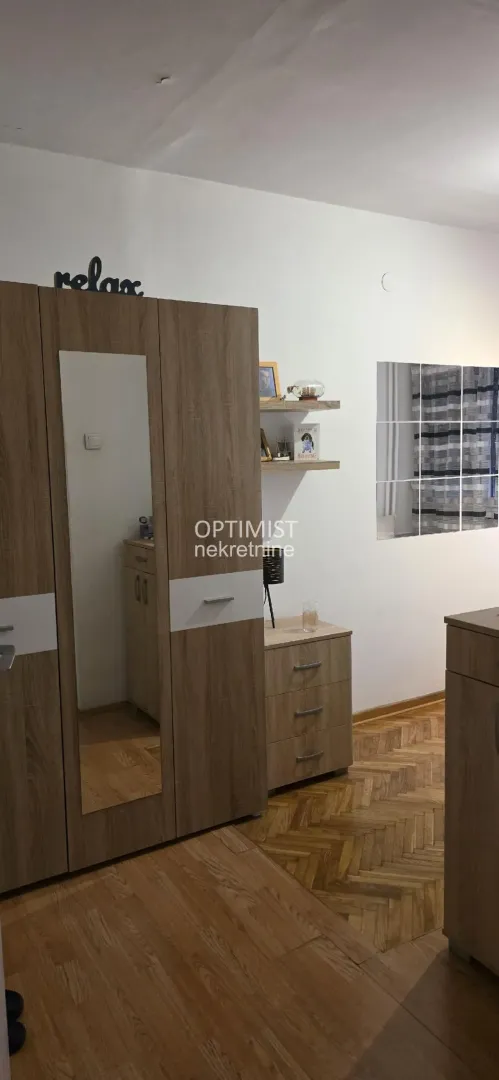 Bedroom with wooden wardrobe, chest of drawers, and parquet flooring.
