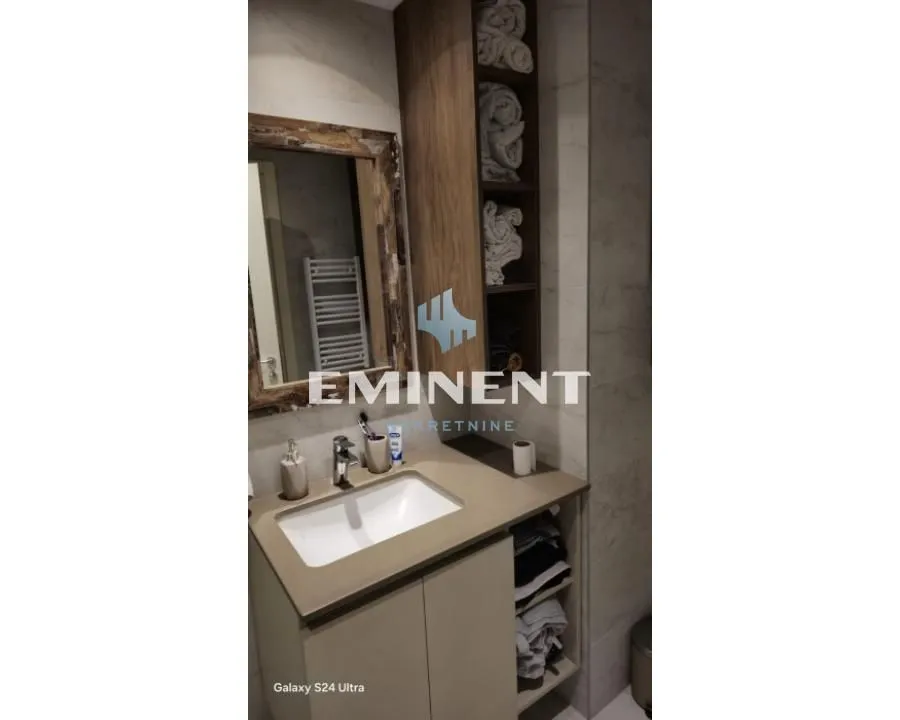 Bathroom with a sink, mirror, and wooden cabinet for towels.