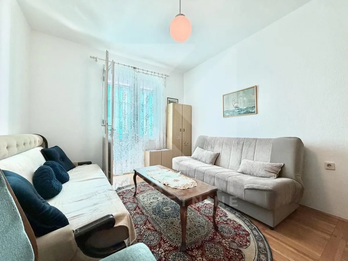 Living room with seating furniture, coffee table, and window with curtains.