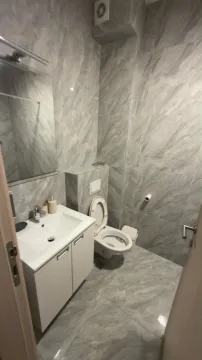 Manje kupatilo obloženo sivim pločicama sa umivaonikom i wc šoljom. - image 9