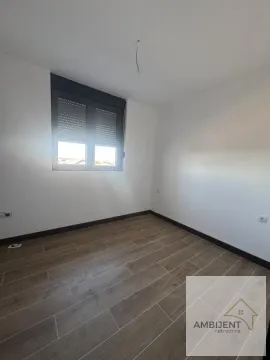 Prazna soba sa belim zidovima, drvenim podom i prozorom sa roletnama. - image 8