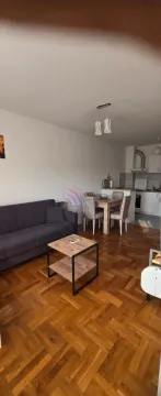 Living room with a sofa and a dining area in the background. - image 2