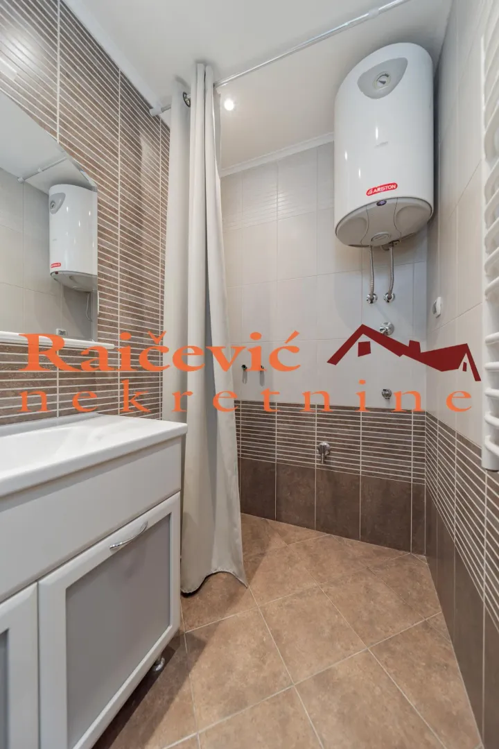 Compact bathroom with a shower enclosure, washbasin, and water heater.