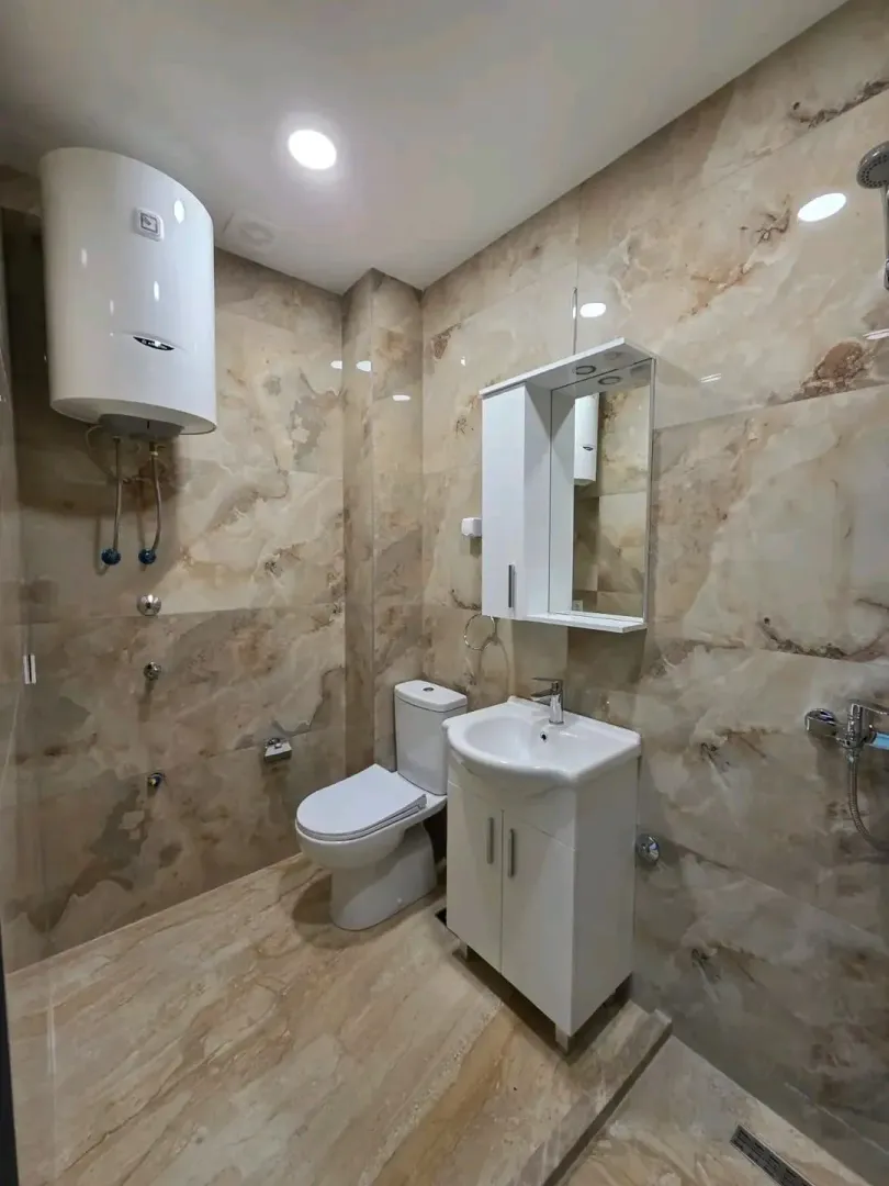 Bathroom equipped with ceramic tiles, washbasin, toilet, and water heater.