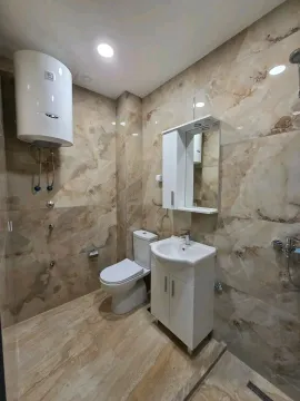 Bathroom equipped with ceramic tiles, washbasin, toilet, and water heater. - image 6