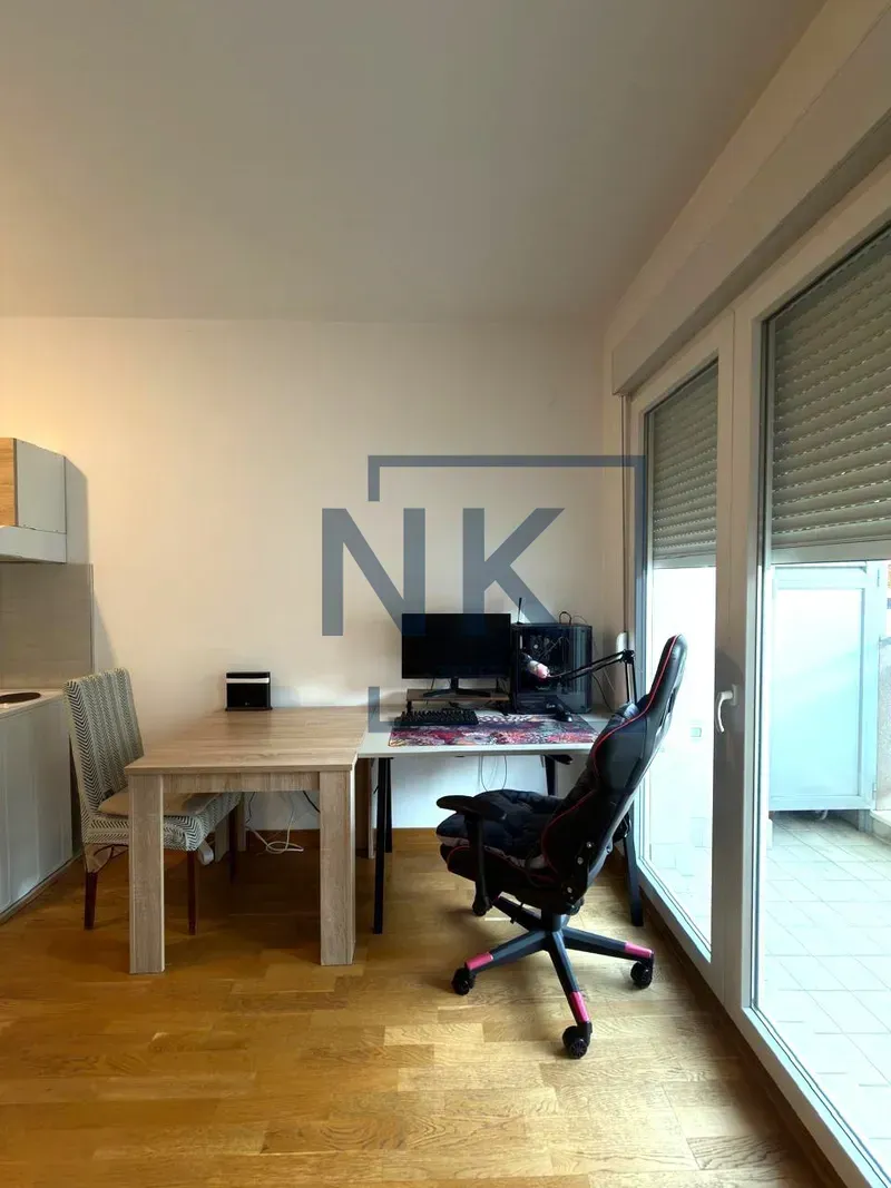 Part of the living room with a desk and computer next to the balcony doors.