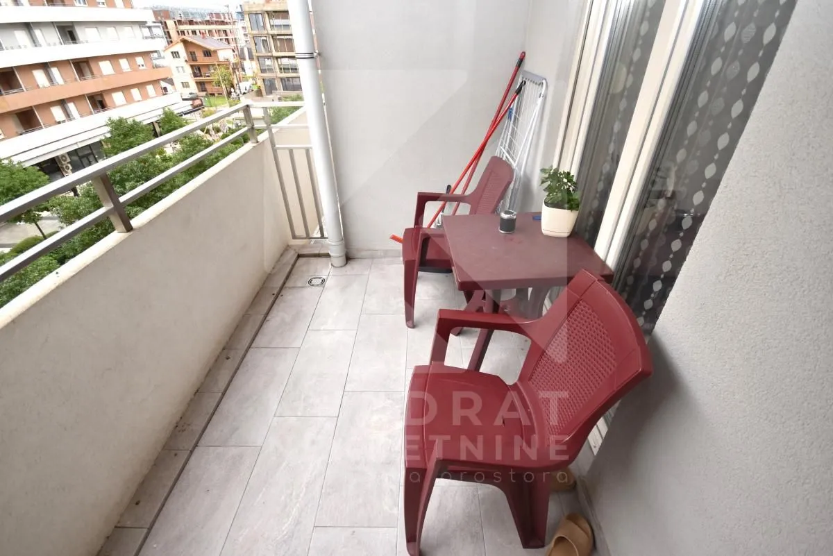 Smaller balcony with a table, chairs and a view of surrounding buildings.