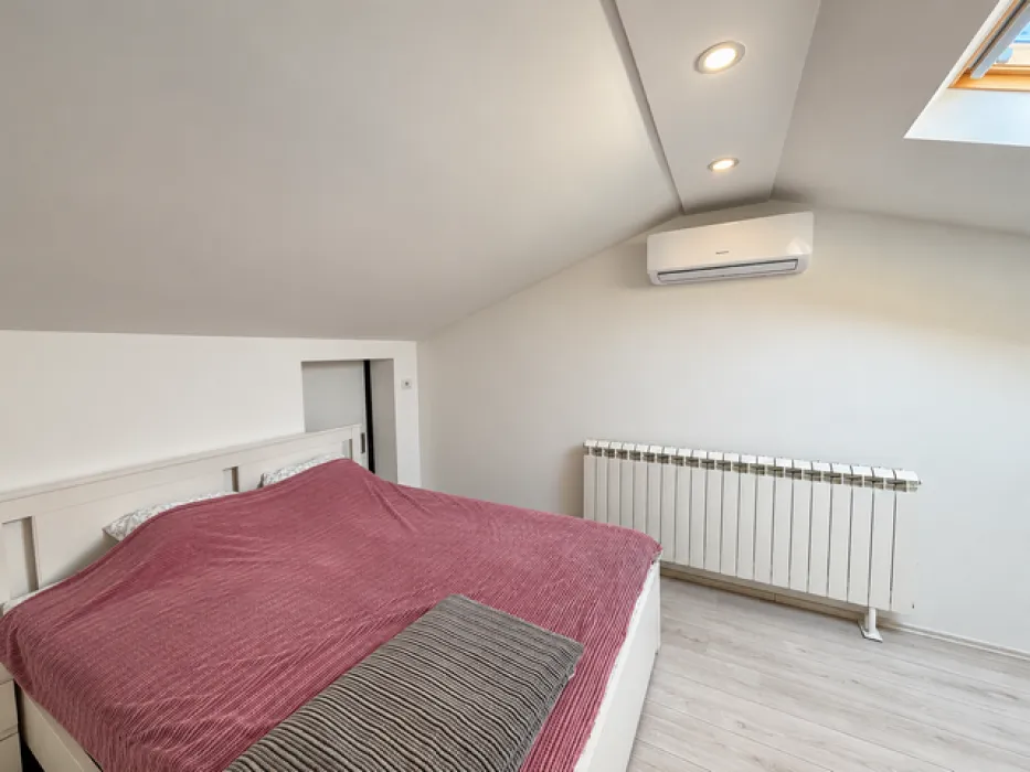Attic bedroom with a double bed, air conditioning, and a skylight.