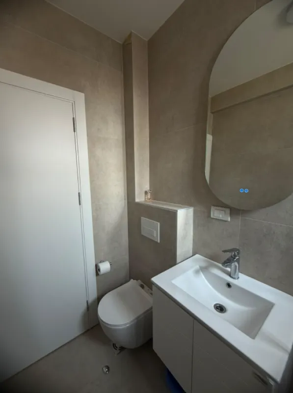 Moderne kupatilo sa umivaonikom, ogledalom i toaletom.