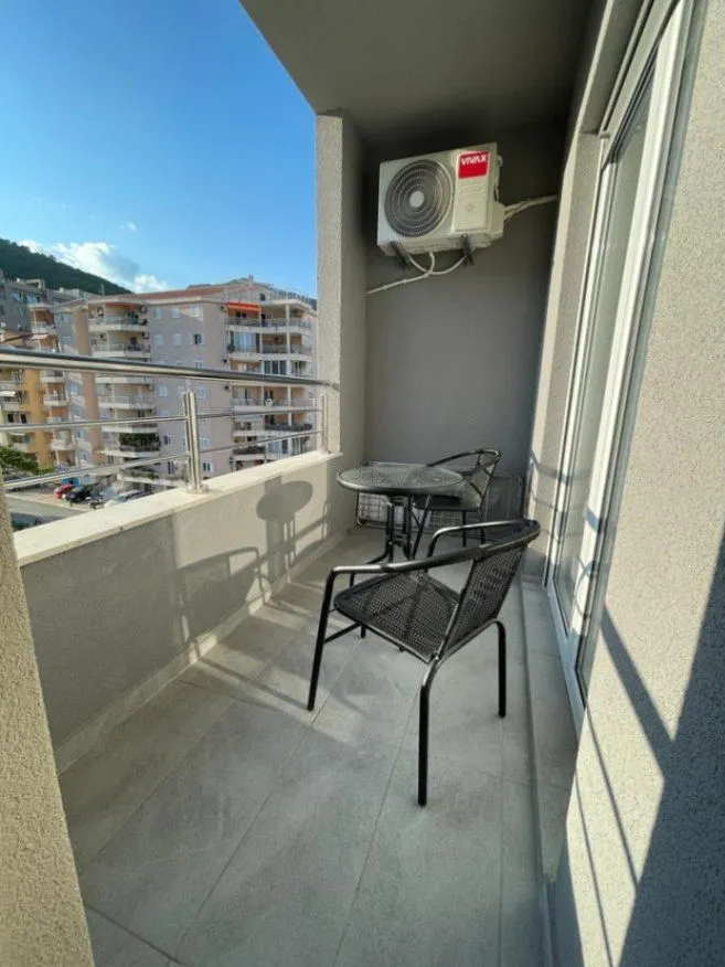 Small furnished balcony with a table, chairs, and an air conditioner.