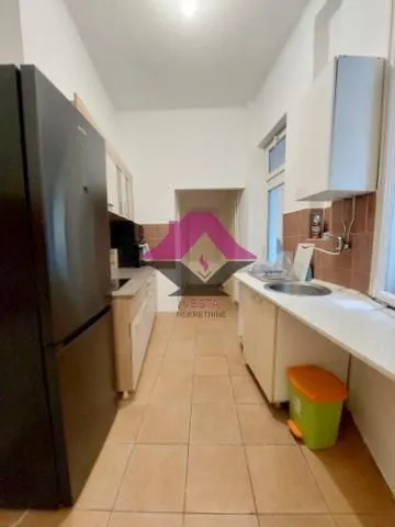 Compact kitchen with a refrigerator and a sink by the window.