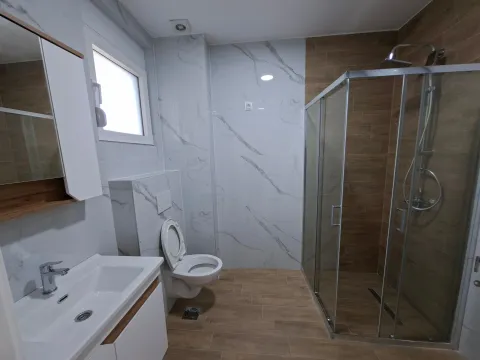 Modernly equipped bathroom with a walk-in shower, washbasin, and toilet. - image 16