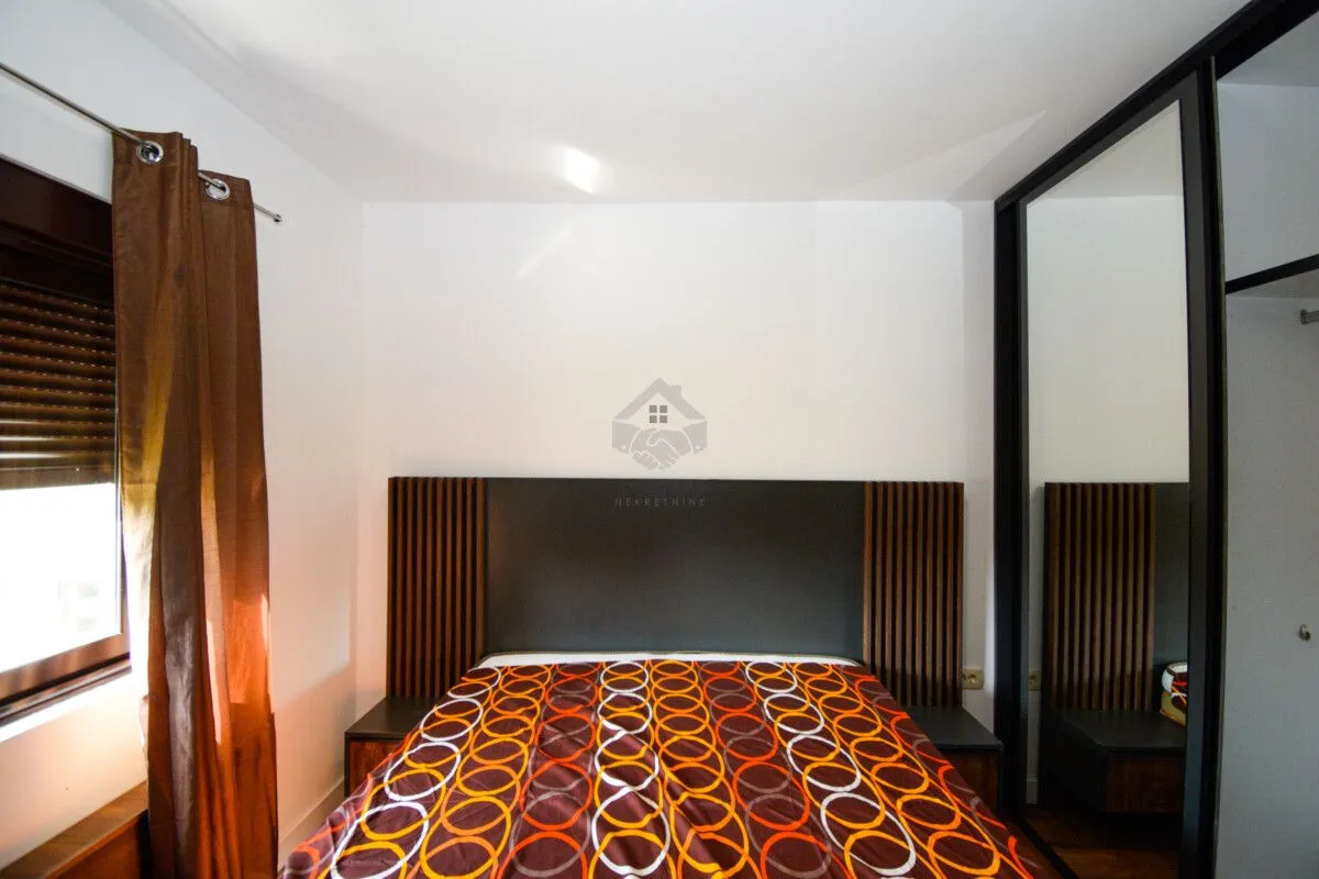 Bedroom with a double bed, headboard, and a large built-in wardrobe with a mirror.