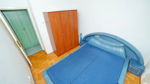 A bedroom with a large blue bed and a wooden wardrobe. - image 8