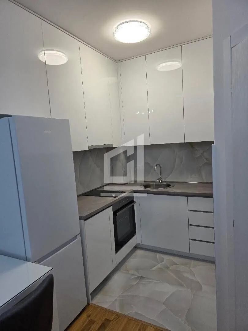 Small modern kitchen with white cabinetry and built-in appliances.