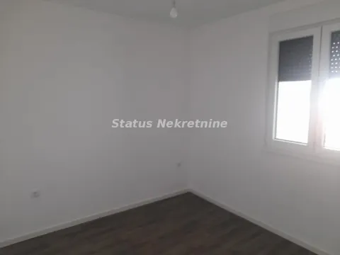 Prazna svetla prostorija sa belim zidovima, tamnim podom i prozorom. - image 2