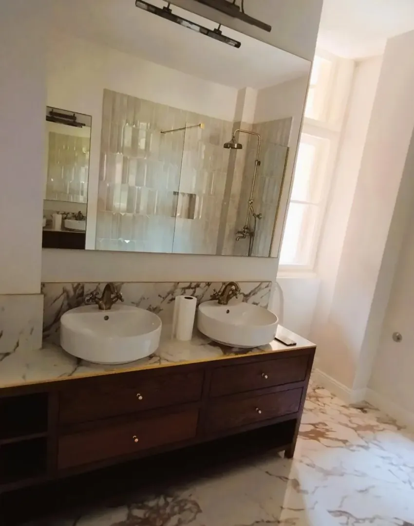 Bathroom with a double vanity, wooden cabinet, and a walk-in shower.