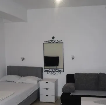 Spavaća soba sa bračnim krevetom, noćnim stočićem i ogledalom na zidu. - image 3