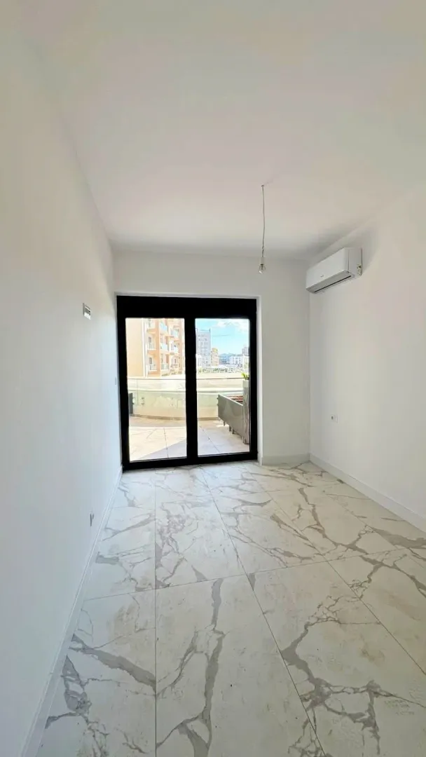 Empty room with white walls, marble tiles, and access to a terrace.