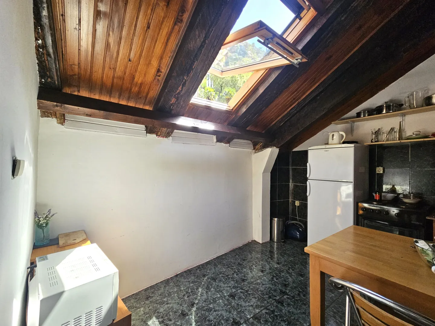 Attic kitchen with a wooden skylight and dining table.