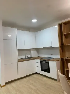 Moderna kuhinja sa bijelim elementima i drvenom radnom površinom. - image 3