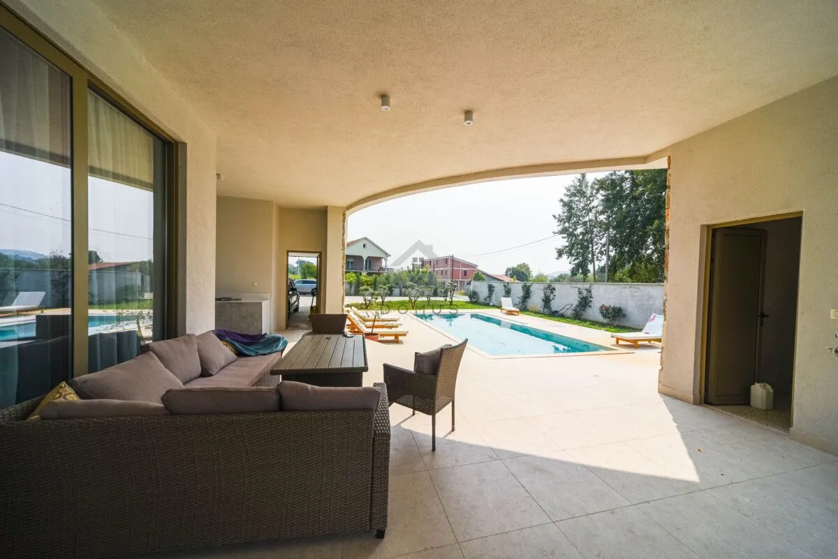 Covered terrace with seating furniture and a view of the swimming pool.