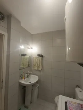 A simple bathroom with a pedestal sink, mirror, and light-colored tiles. - image 8