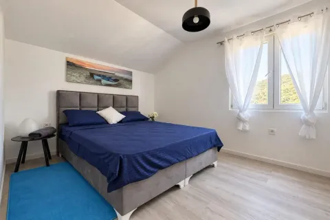 Svjetla spavaća soba sa bračnim krevetom, bijelim zidovima i prozorom koji gleda na prirodu. - image 6