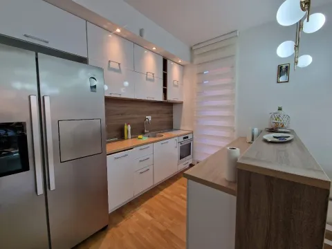 Modern kitchen with white cabinets, a large refrigerator, and a wooden breakfast bar. - image 19