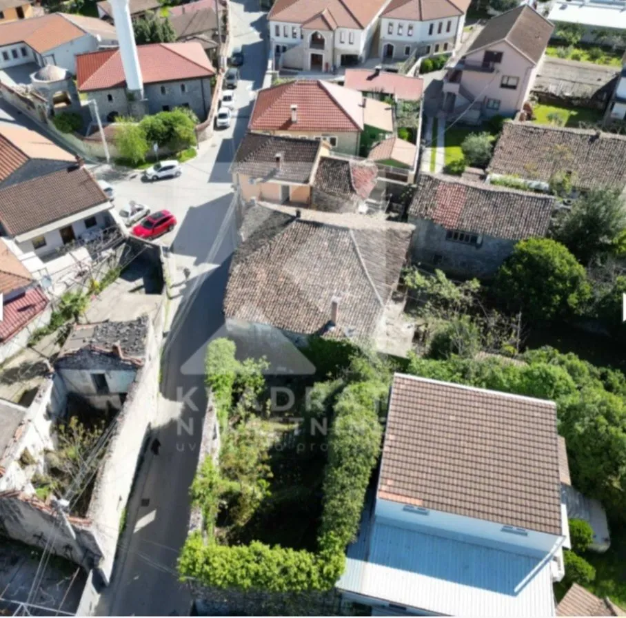 Pogled iz vazduha na naselje i okolne kuće sa ulicom.