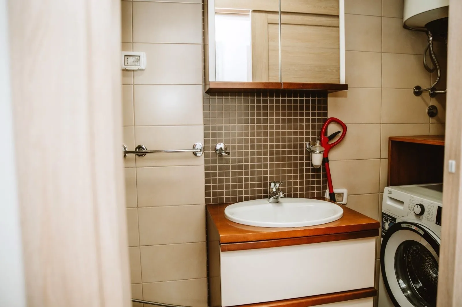 Bathroom with a modern sink vanity, mirror, and washing machine.