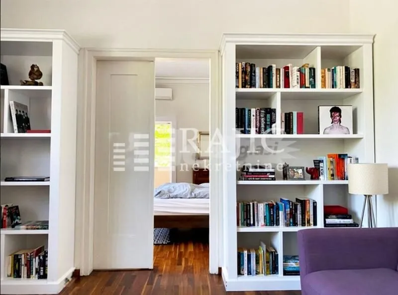 Living room with white bookshelves and a view into the bedroom.