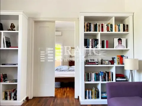 Living room with white bookshelves and a view into the bedroom. - image 2