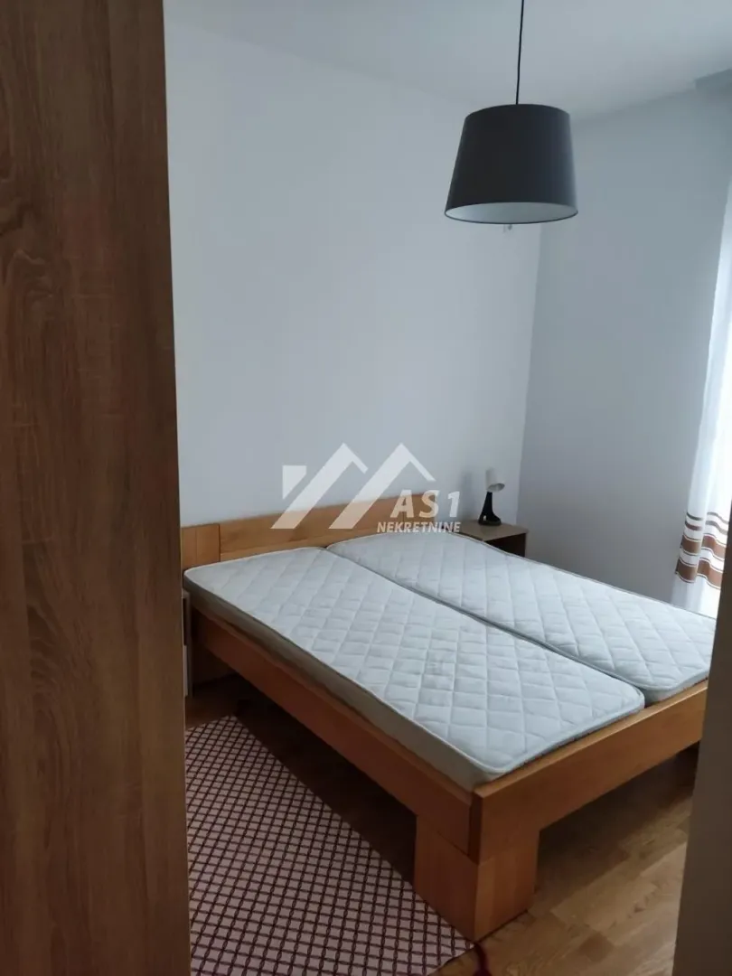 Spavaća soba sa bračnim krevetom i drvenim podom.