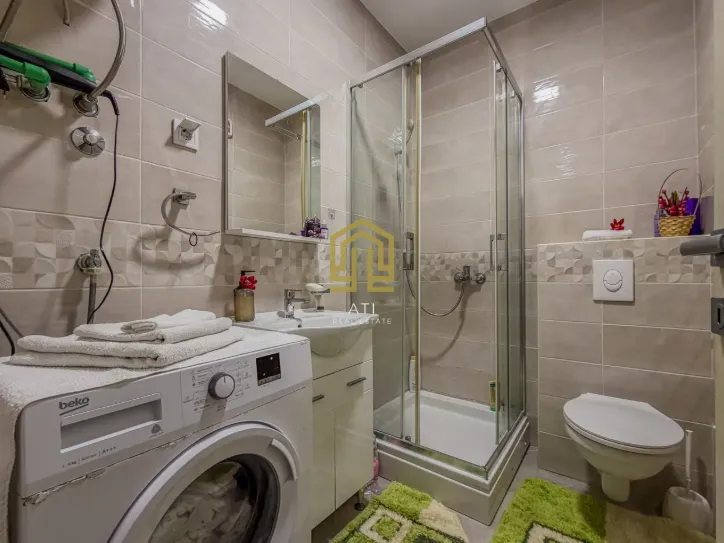 Moderno kupatilo sa tuš kabinom i veš mašinom.