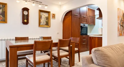 Dining area with a wooden table and chairs, with a view of the kitchen. - image 5