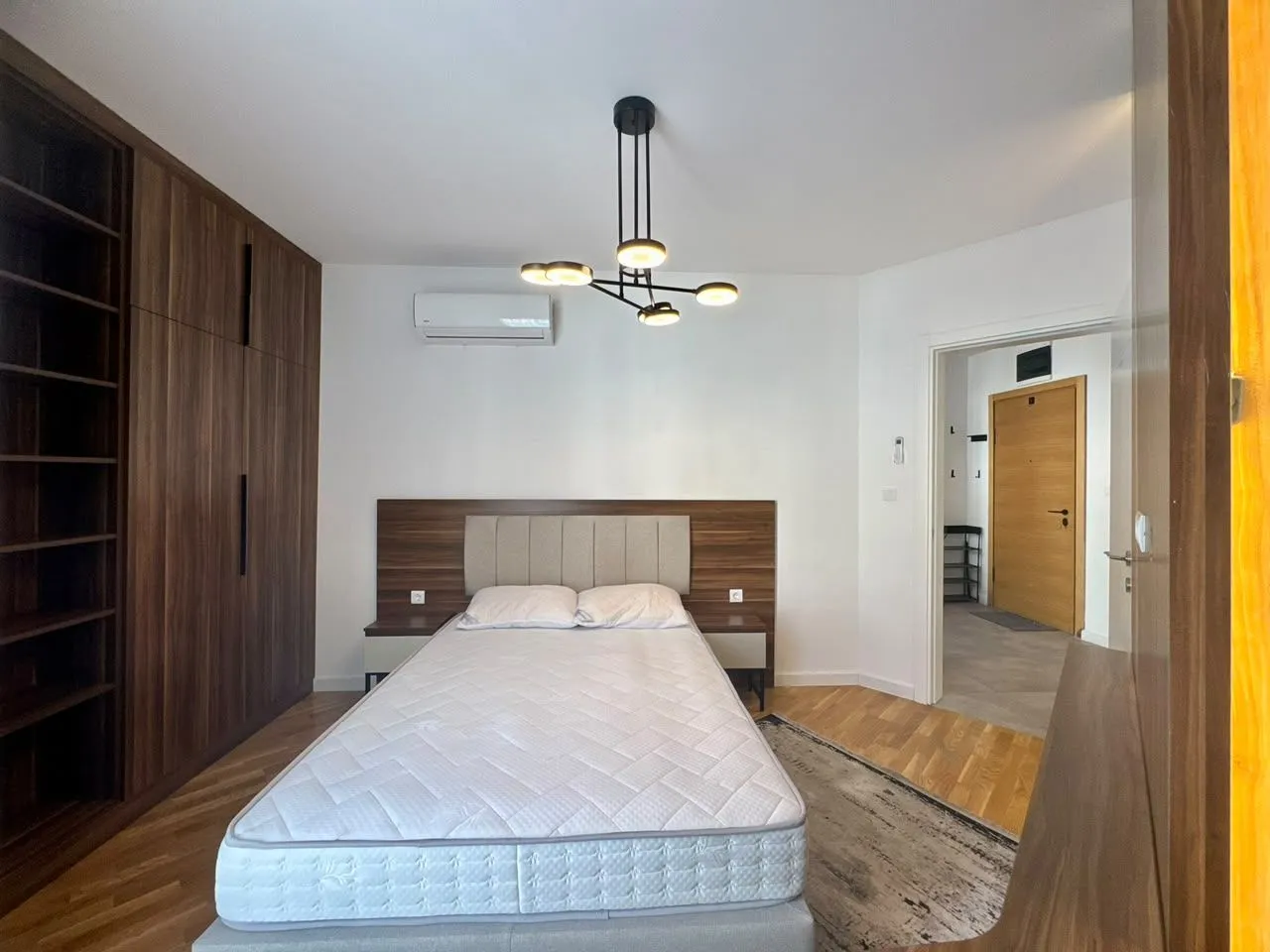 Furnished bedroom with a double bed, large wardrobe, and modern chandelier.