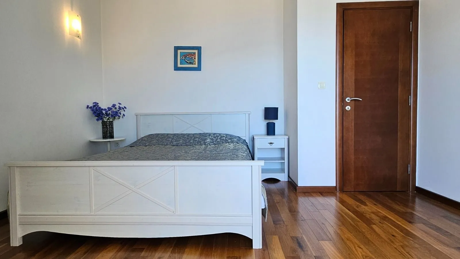 Spavaća soba sa bijelim krevetom i drvenim podom.
