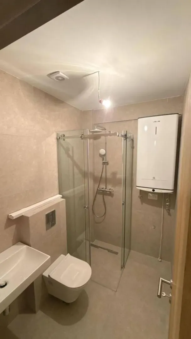 Small bathroom with a shower cabin, washbasin, and toilet.