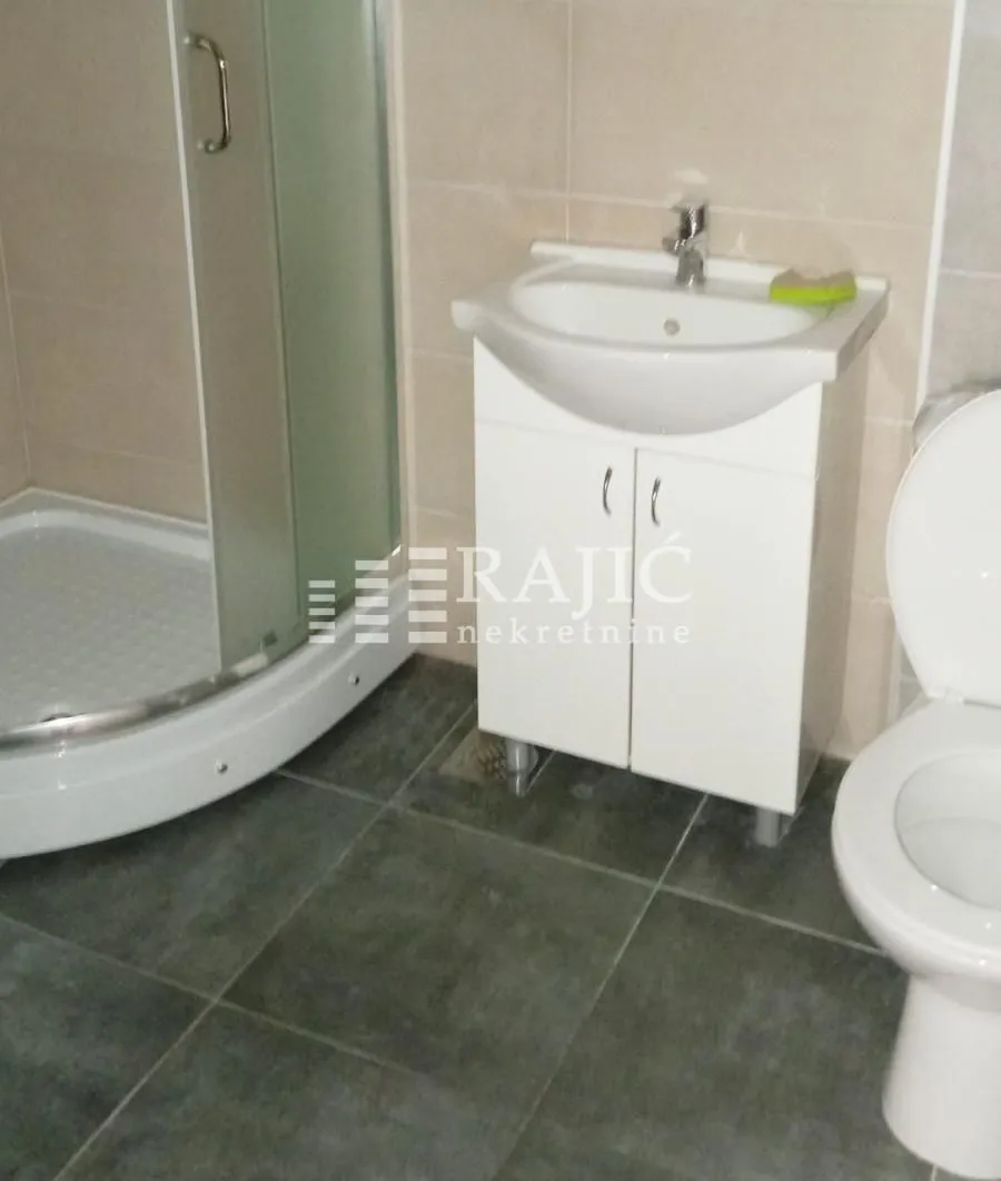 Smaller bathroom with a shower cabin, washbasin, and toilet.