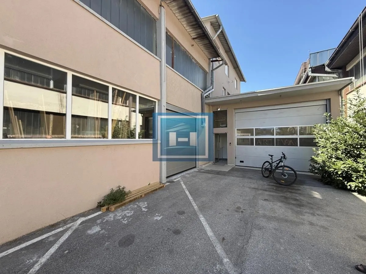 Exterior view of the commercial building with a yard and garage doors.