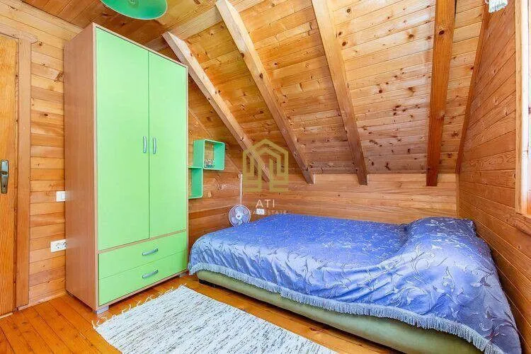 Wood-paneled attic bedroom with a bed and a wardrobe.