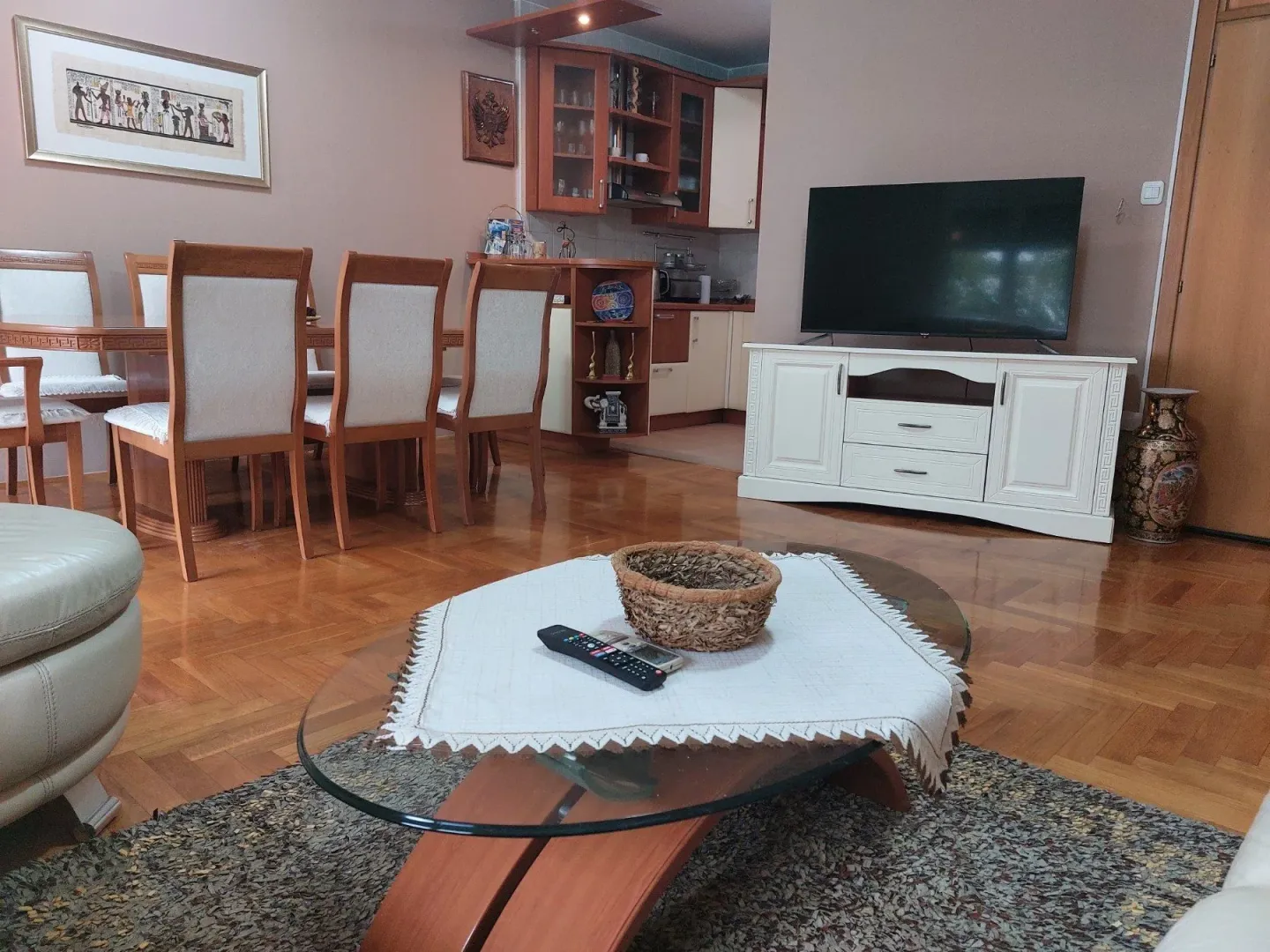 A bright living room with a dining table, coffee table, and TV.